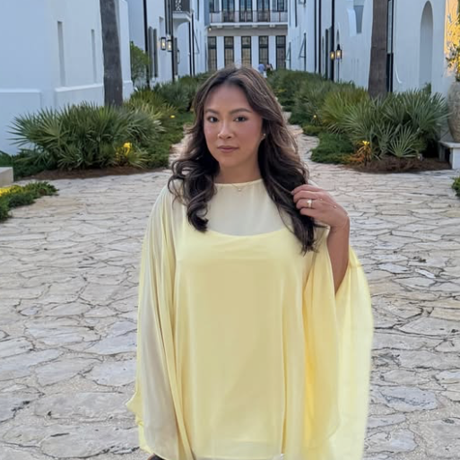 New Orleans influencer Ain't That Phancy (Karen Phan) stands outdoors in a sheer, draped yellow dress.