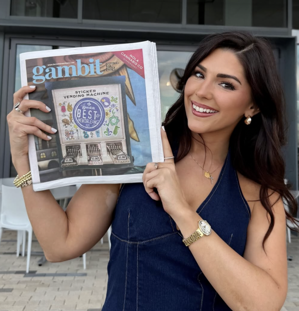 New Orleans influencer Eating With Cait (Caitlin Minshew) holds up a copy of Gambit, where she's recognized as their 2025 Best Local Food Social Media Account and Best Local Influencer/Content Creator.