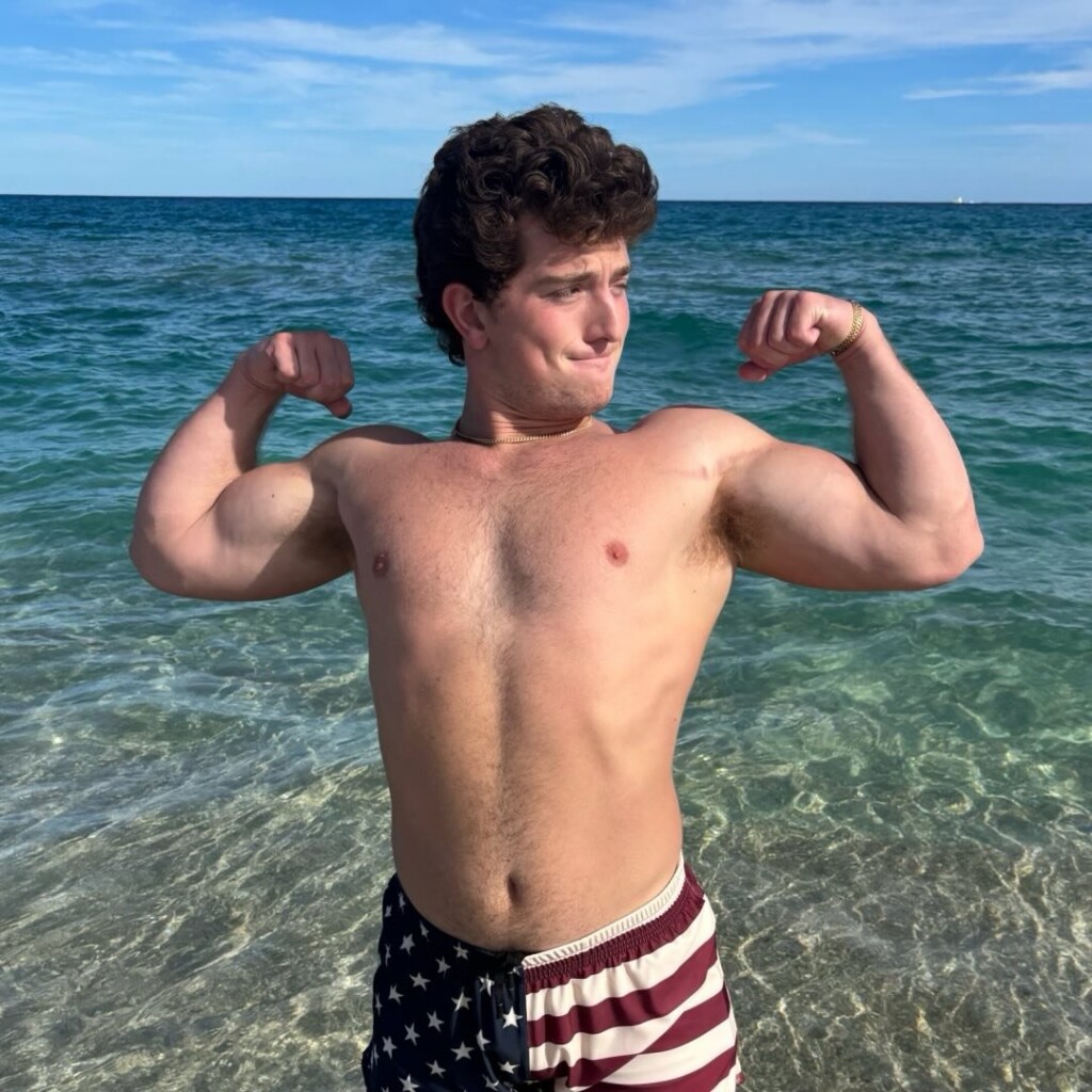 New Orleans influencer Jesse Blu Fit (Jesse Blumenfeld) flexes his muscles as he stands out in the ocean in the sunshine.