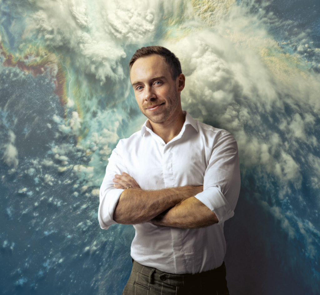New Orleans influencer Scot Pilié poses in front of a weather map with a confident expression, his arms crossed.