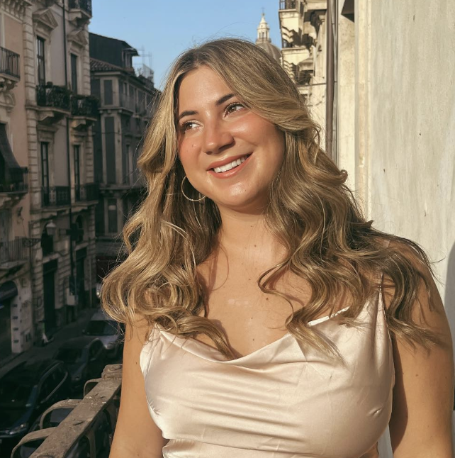 New Orleans influencer The Filet Mignon (Mignon Holton) stands on a balcony at golden hour, smiling off towards the sunset.