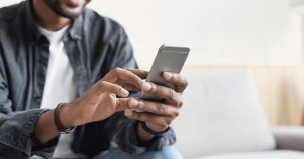 A business manager uses a smartphone while sitting on their couch to complete Reddit business verification